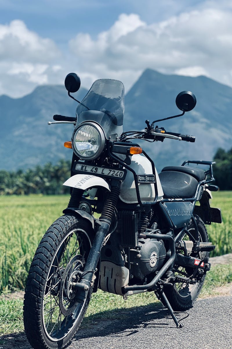 A motorcycle parked on a rural road with mountains under a cloudy sky. Ideal for travel and adventure themes.