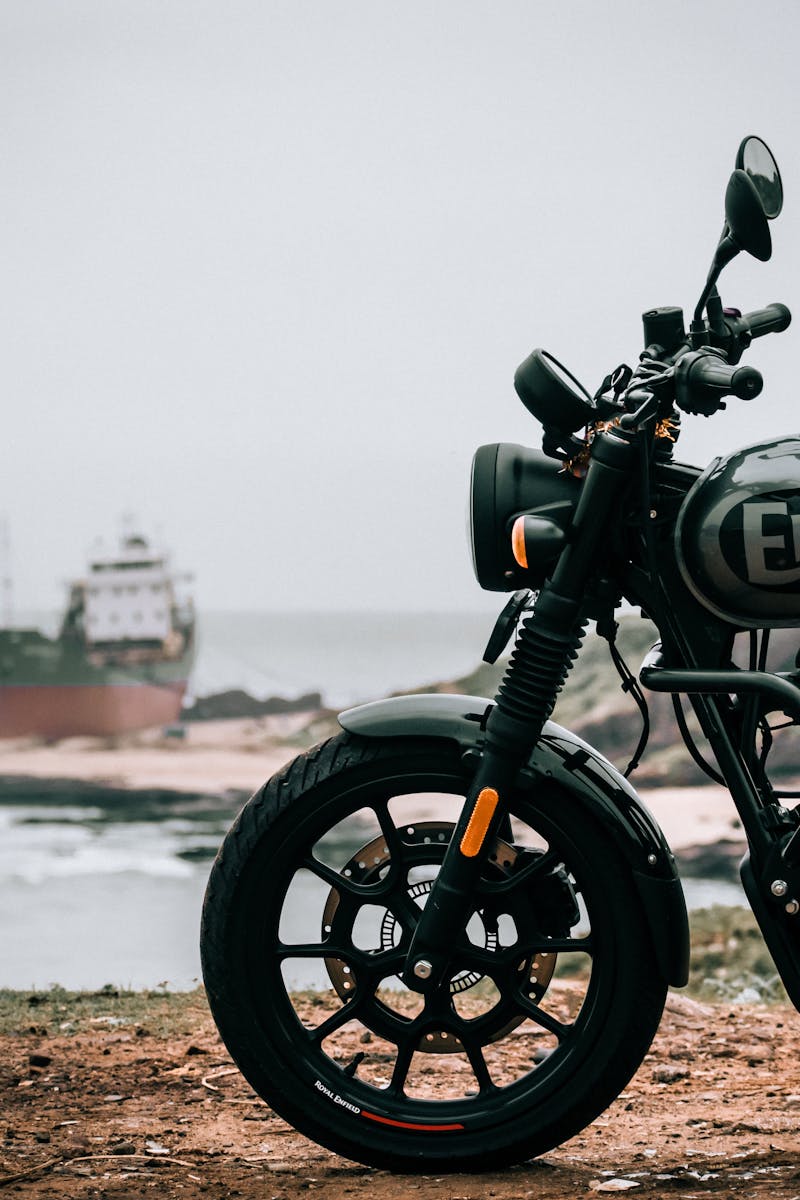 Royal Enfield Hunter 350 motorcycle parked with a ship in the background near the ocean.
