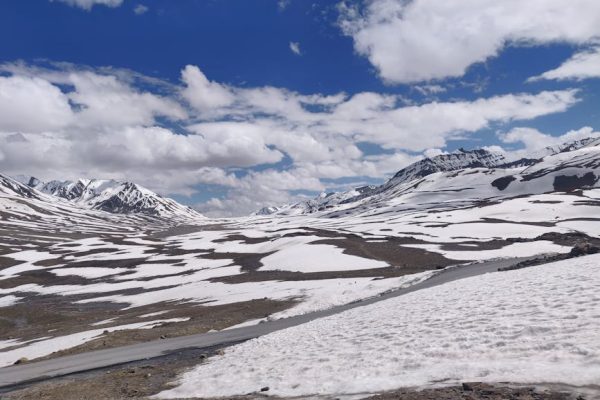 Serene winter view of Baralacha La Pass with snow-capped mountains under a blue sky.