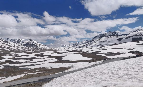 Serene winter view of Baralacha La Pass with snow-capped mountains under a blue sky.