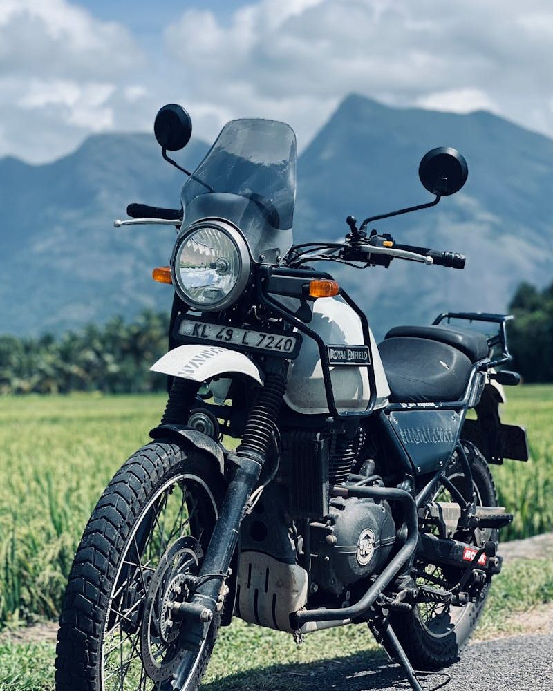 A motorcycle parked on a rural road with mountains under a cloudy sky. Ideal for travel and adventure themes.