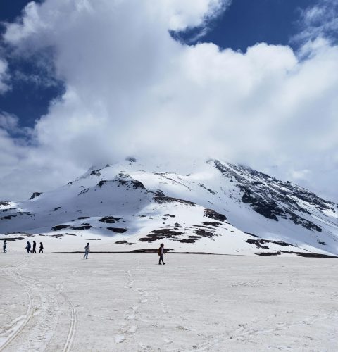 Scenic view of snow-capped peaks under cloudy skies in Rohtang, Himachal Pradesh.