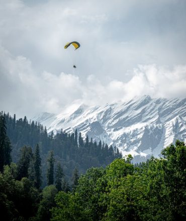 Experience the thrill of paragliding above the snowy mountains of Solang Valley, India. A breathtaking adventure awaits.