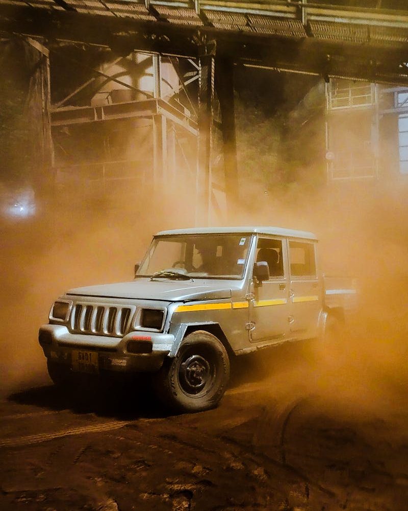 Mahindra SUV kicks up dust in an industrial setting in Amona, India, showcasing rugged performance.