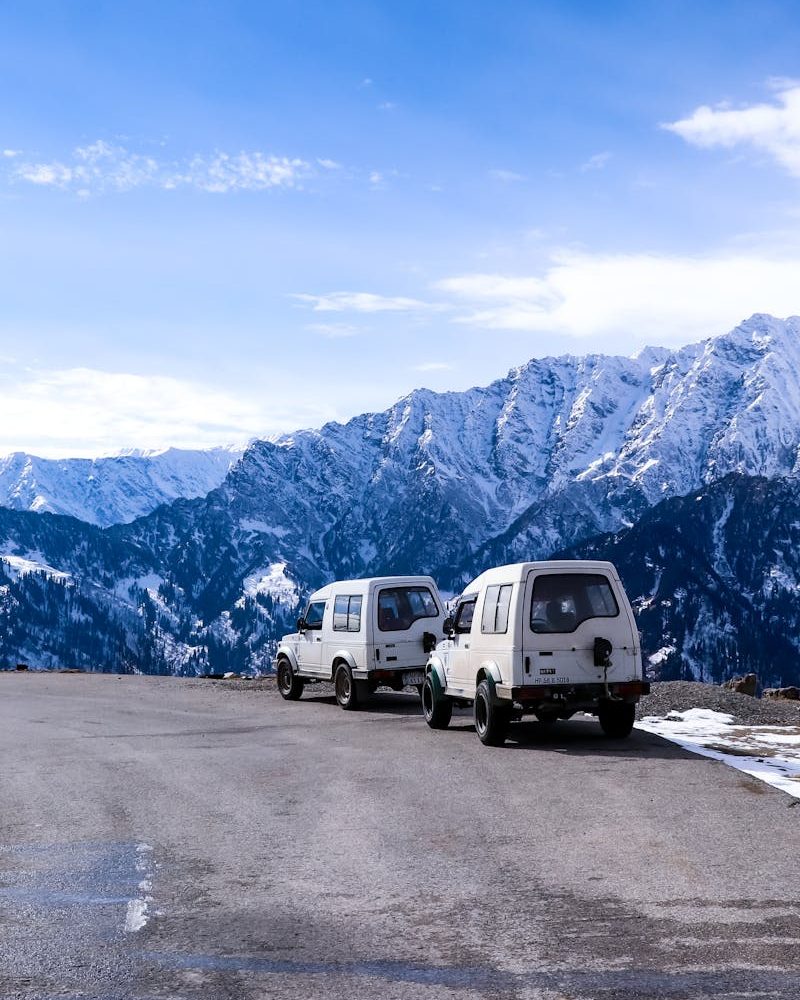 Idyllic winter road trip scene with vehicles and mountains in Himachal Pradesh.